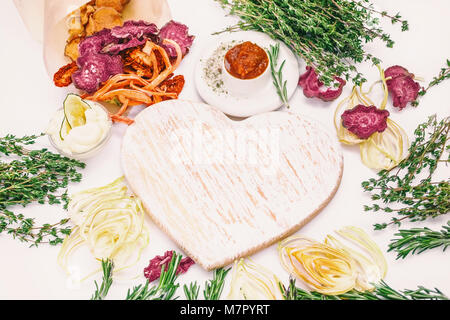 Homemade colorful chips of different fresh vegetables - beets, sweet potatoes, carrots, cucumber, onions, rosemary and thyme on a light background aro Stock Photo