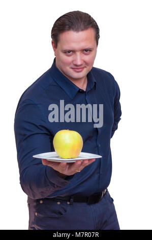 Portrait of young athletic elegant man with blue shirt holds one big apple on white plate. Stock Photo