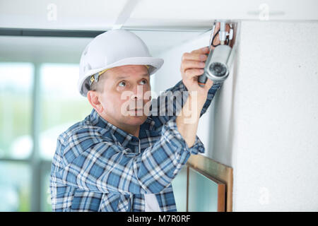 senior technician adjusting cctv camera on wall Stock Photo