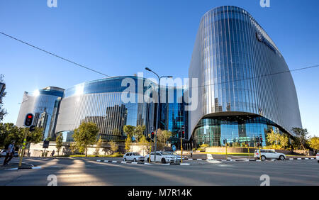 Johannesburg, South Africa - March 8, 2018: Glass fronted modern building with road in foreground. light reflection on road. Stock Photo