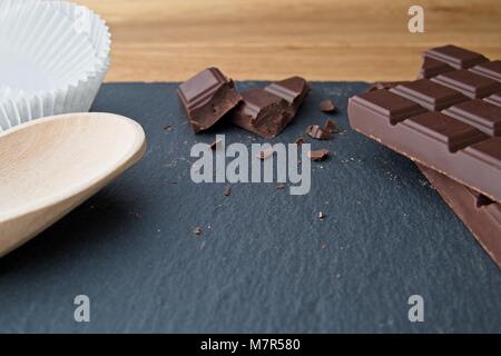 Broken plain chocolate with baking utensils on slate background Stock Photo