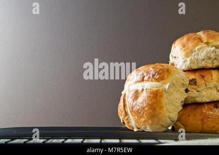 Stack of hot cross buns on wire cooling rack with plain background Stock Photo