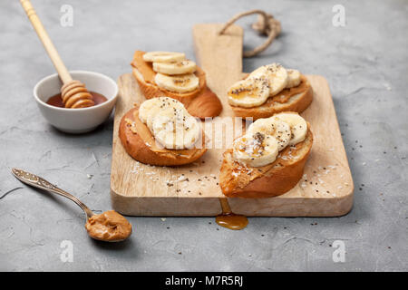 healthy breakfast. sandwich with peanut butter, banana, honey, chia seeds and coconut sprinkled on a gray concrete background Stock Photo