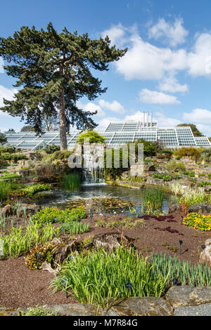 London, UK - April 18, 2014. Rock garden and Princess of Wales Conservatory in Kew Botanic Gardens. The gardens were founded in 1840. Stock Photo
