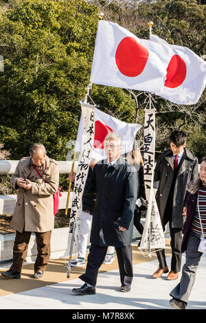 Japan, Ise Grand Shrine, Naiku, inner shrine. Moden day pilgrams on bridge carrying Japanese flag banners. Stock Photo