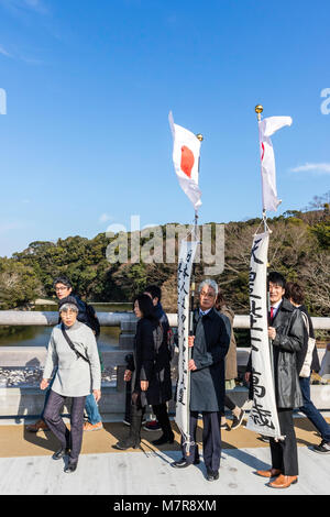 Japan, Ise Grand Shrine, Naiku, inner shrine. Moden day pilgrams on bridge carrying Japanese flag banners. Stock Photo