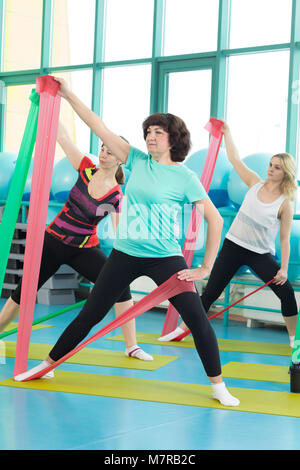 Women doing gym exercises using latex fitness bands Stock Photo
