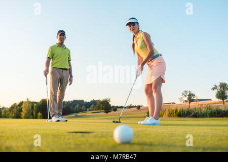 Competitive woman looking at the golf ball with disappointment Stock Photo