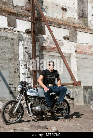 Man sitting on his Suzuki Cafe Racer motorcycle Stock Photo