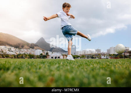 Boy kicking a football in a playground. Low angle view of a boy playing football in a playfield.