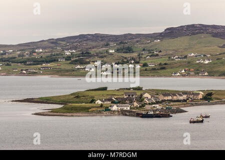 Aultbea, Scotland - June 9, 2012: Harbor of Aultbea with pier and a few fishing vessels. Port at end of peninsula in gray waters of Loch Ewe. Green hi Stock Photo