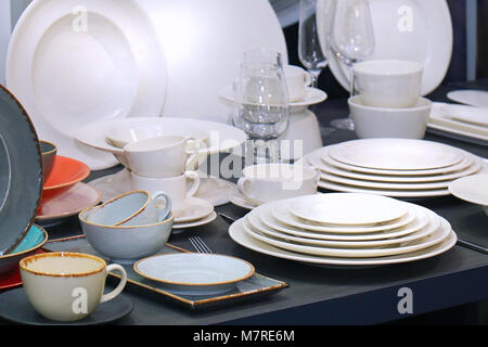 White porcelain plates stacked on table with ceramic cups Stock Photo