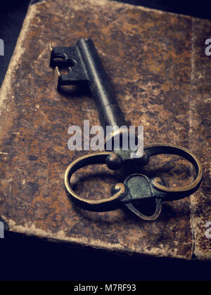 Old used book with a big key, vintage or retro stylized background Stock Photo