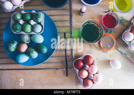 Dyeing eggs for Easter holidays, coloring with different color and tonality using food colorant over a gray concrete background Stock Photo
