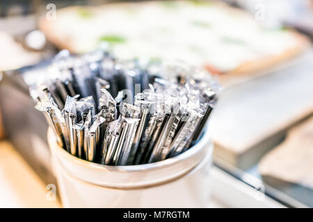 Macro closeup of many black plastic spoons wrapped in plastic packaged fast food in cup container in restaurant Stock Photo