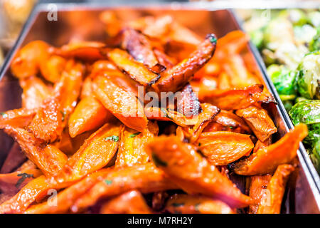 Macro closeup of oily greasy roasted shiny sweet potato slices in tray on display in buffet, catering, deli, store, shop grocery market fresh Stock Photo