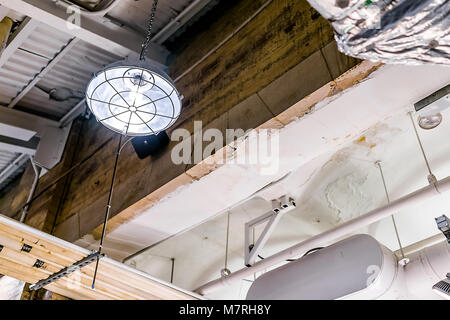 Industrial lamp up hanging on ceiling in warehouse, grunge old building interior closeup, metal pipes, concrete Stock Photo