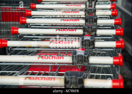 Parked shopping carts equipped with coin-operated locking mechanisms in of shopping mall Auchan in the beginning of law restriction for Sunday shoppin Stock Photo