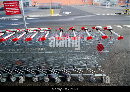 Parked shopping carts equipped with coin-operated locking mechanisms in of shopping mall Auchan in the beginning of law restriction for Sunday shoppin Stock Photo