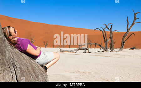 Woman leans on tree in desert surrounded. Enjoying and relaxing. Stock Photo