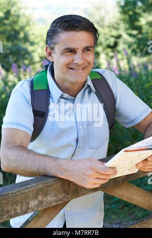 Mature Man Hiking In Countryside Looking At Map Stock Photo
