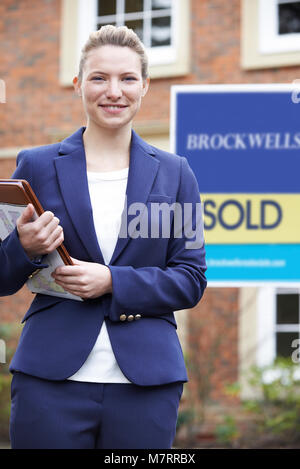 Portrait Of Female Realtor Standing Outside Residential Property Stock Photo
