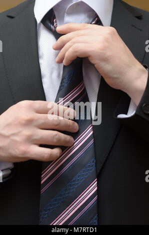 Businessman in a business suit straightens his tie Stock Photo