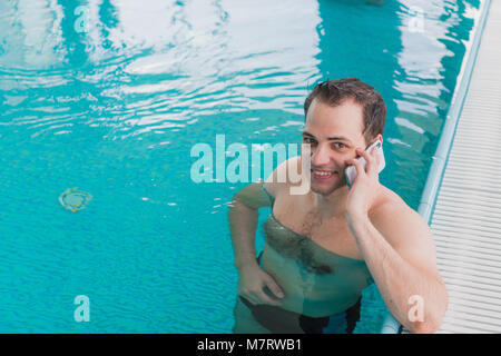 Man use the cellphone in the edge of the pool Stock Photo