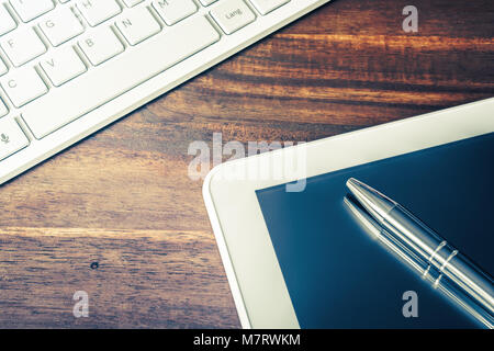 Closeup Of A White Tablet And Grey Pencil Lying Next To A White Keyboard On Wooden Table Stock Photo
