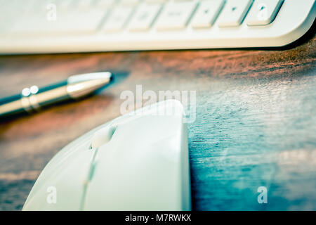 Macro Of A White Computer Mouse In Front Of A Pen And A White Keyboard On Wooden Table Stock Photo