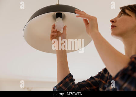 Woman replacing light bulb at home. Power save LED lamp changing Stock Photo