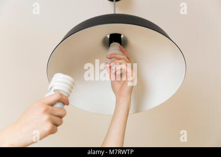 Woman replacing light bulb at home. Power save LED lamp changing Stock Photo