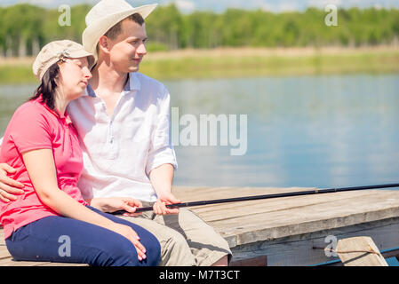 Barefoot happy couple on the pier to catch a fish on a beautiful lake Stock Photo