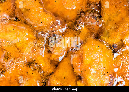 Frying the meat wrapped in breadcrumb on the pan, close up. Fried chicken in oil. Stock Photo