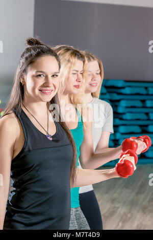 horizontal close-up portrait of three girls in training with dumbbells Stock Photo