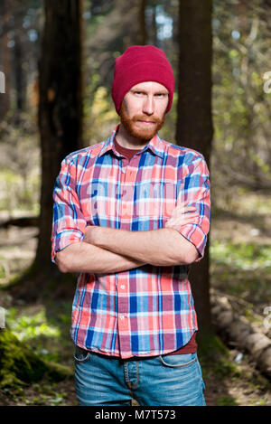 portrait of a man with a beard in a plaid shirt and hat in the woods Stock Photo
