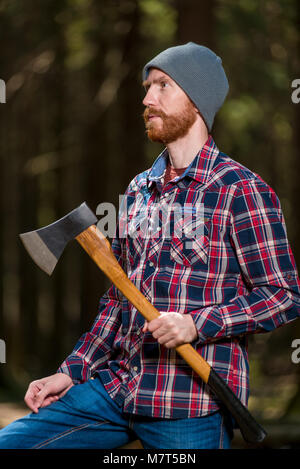 vertical portrait of a lumberjack with an ax in the summer forest Stock Photo