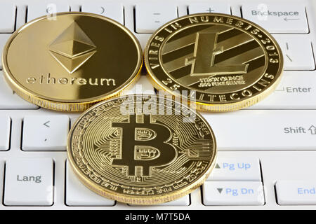 Physical golden bitcoin, ethereum and litecoin coin lying on computer keyboard. Stock Photo