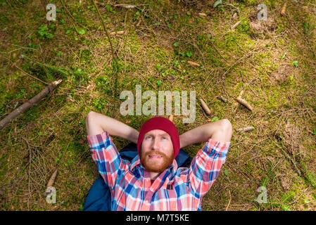 forester resting in the forest, lying on the ground surrounded by cones Stock Photo