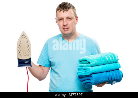 portrait on white background man with iron and a pile of ironed towels isolated Stock Photo