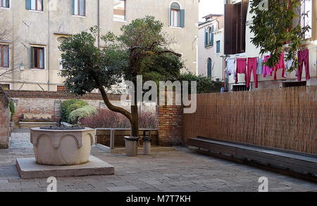Venice, Italy. Courtyard with well, historical buildings, linen, and clothes in Santa Croce Stock Photo