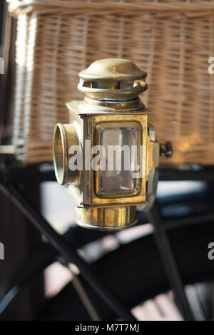 Brass lantern on vintage vehicle with basket and wheel in background Stock Photo