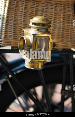 Brass lantern on vintage vehicle with basket and wheel in background Stock Photo