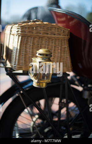 Brass lantern on vintage vehicle with basket and wheel in background Stock Photo