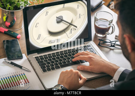 Energy efficiency concept. Vintage car gauge on a computer screen, man working, office background Stock Photo