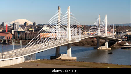 It's a clear day in Portland Oregon at Tilikum Crossing as people traverse the river with Mount St. Helens in the background Stock Photo