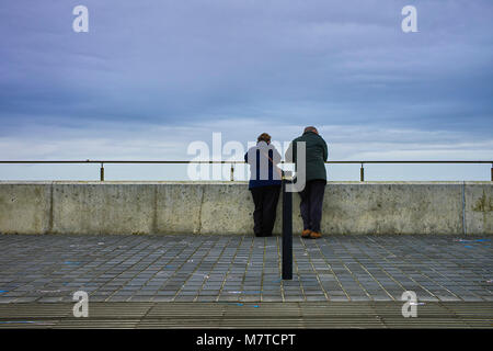Middle aged man and woman leaning on the sea wall at Margate Stock Photo