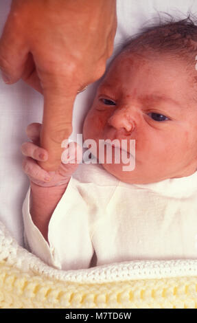 newborn baby of Costa Rican origin grasping adult's finger Stock Photo