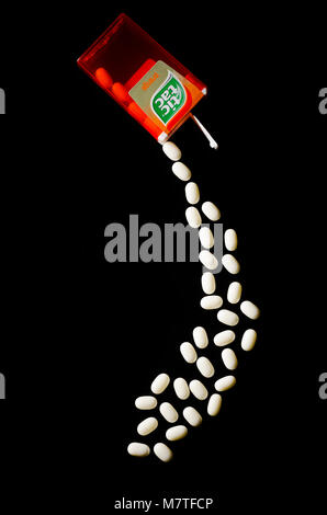 Falling tic tacs isolated on dark background. Tic tacs are manufactured by Italian confectioner Ferrero and were first produced in 1968. Stock Photo