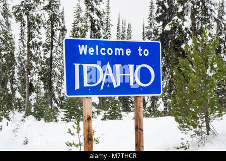 Idaho welcome sign with snow falling in winter on road at Lost Trail Pass in Bitterroot Mountains, Idaho, USA Stock Photo